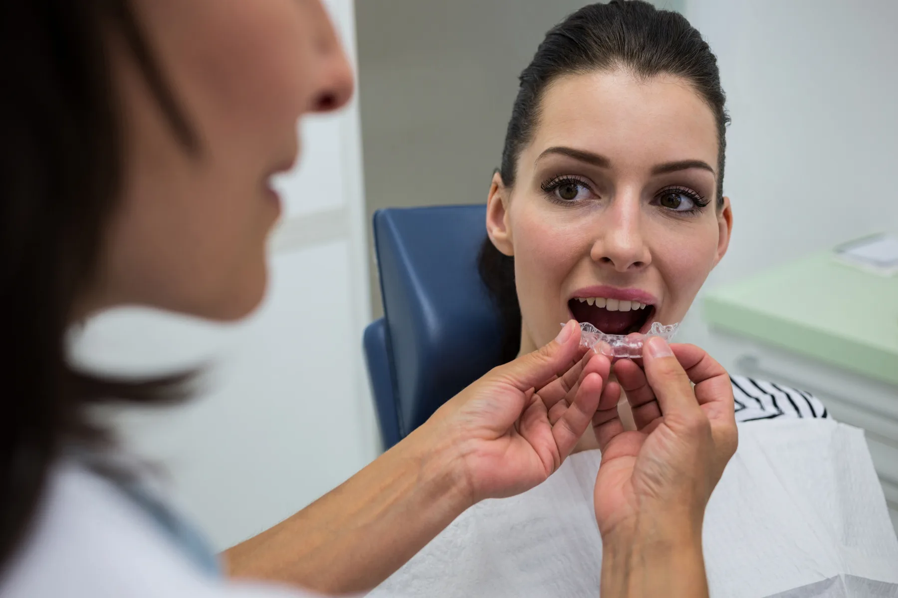A dentist helping a patient try a clear aligner