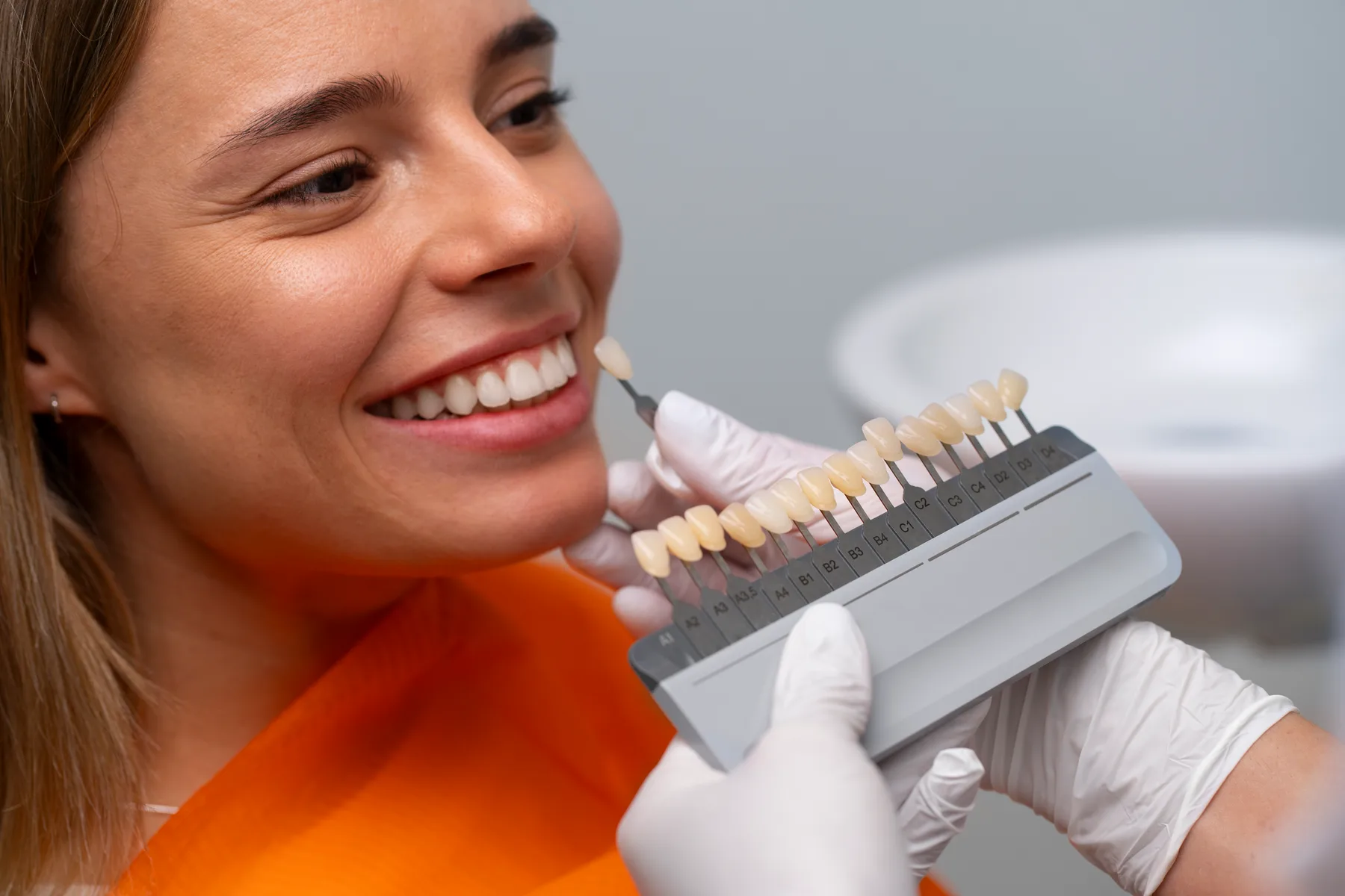 A patient comparing a dental shade guide
